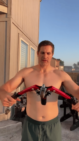 Man using arm trainer outdoors for strength training workout.