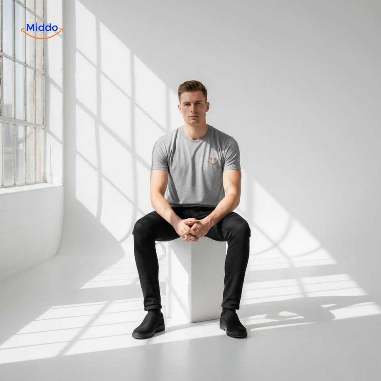 Grey smiley print t-shirt in minimalist seated studio pose.