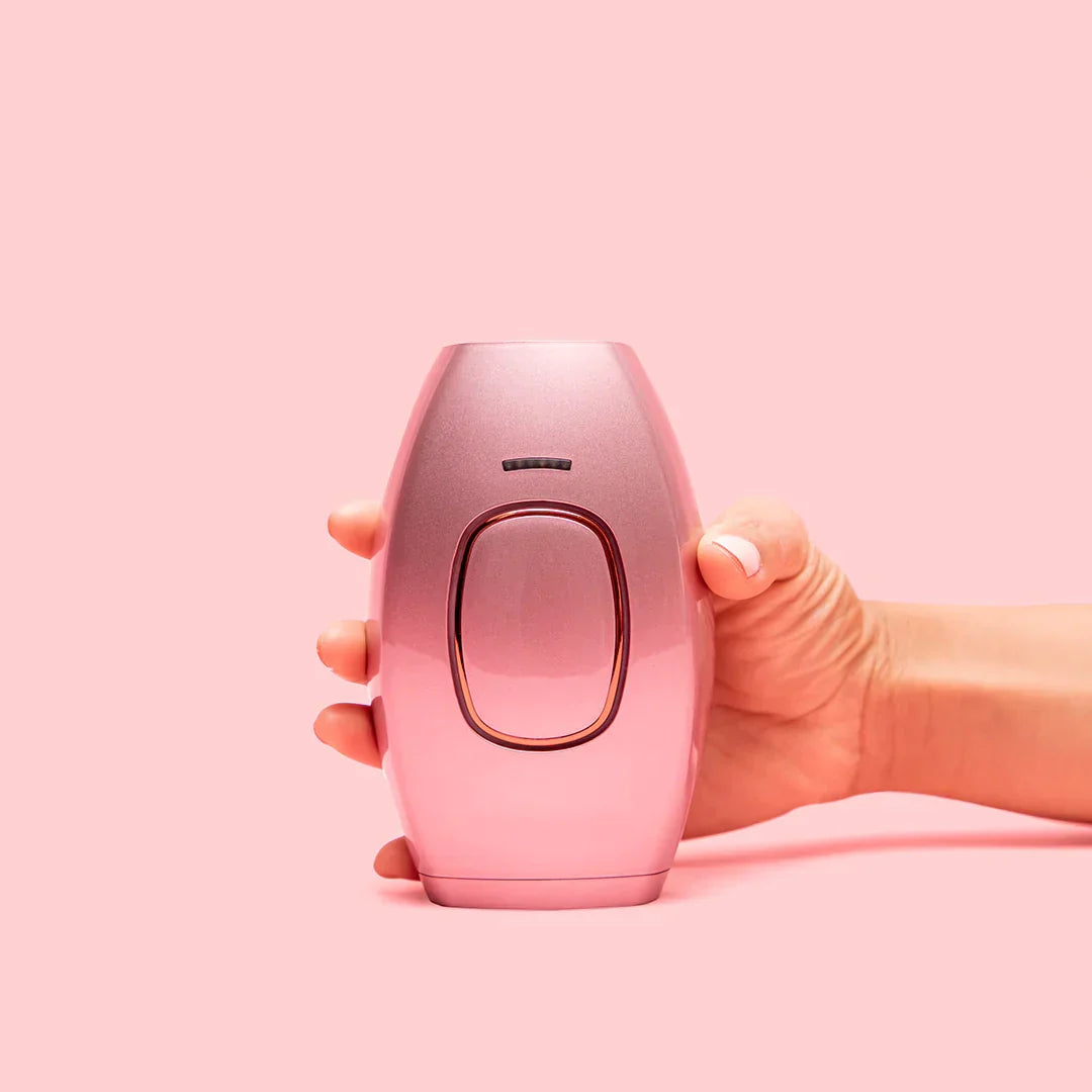Handheld pink IPL hair remover fitting comfortably in hand.