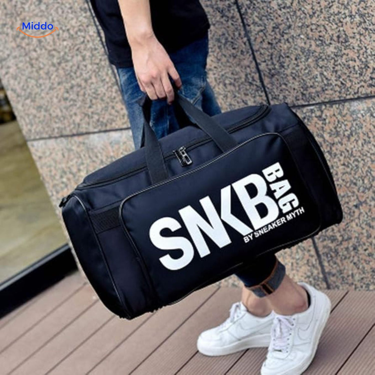 Person carrying SNKRPro travel bag outdoors on city streets.