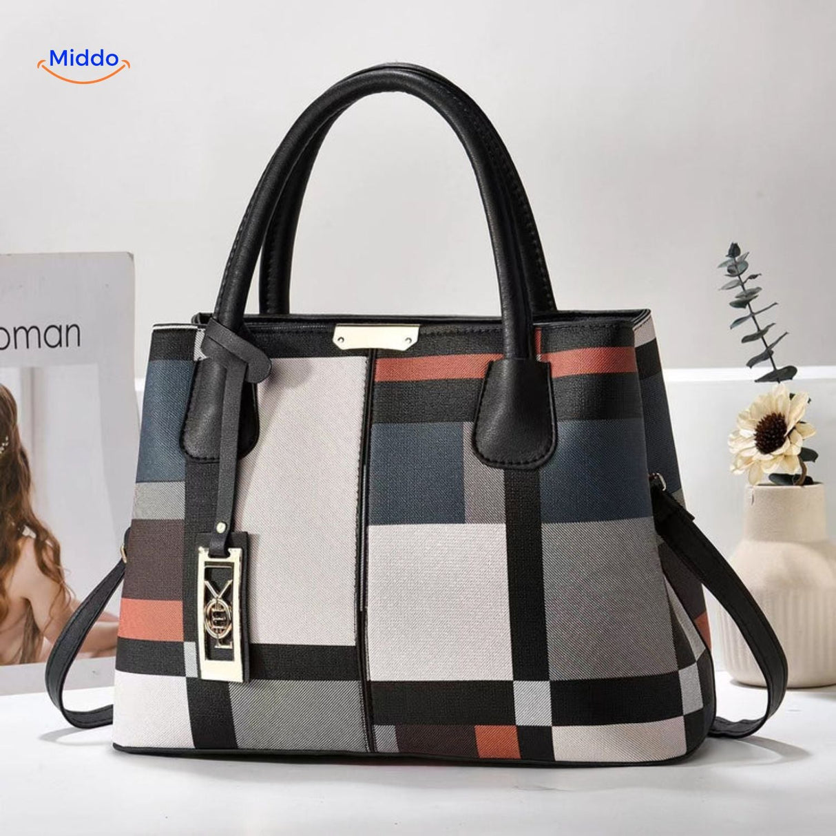 Styled tote bag with decorative pom-pom and supportive shoulder straps.
