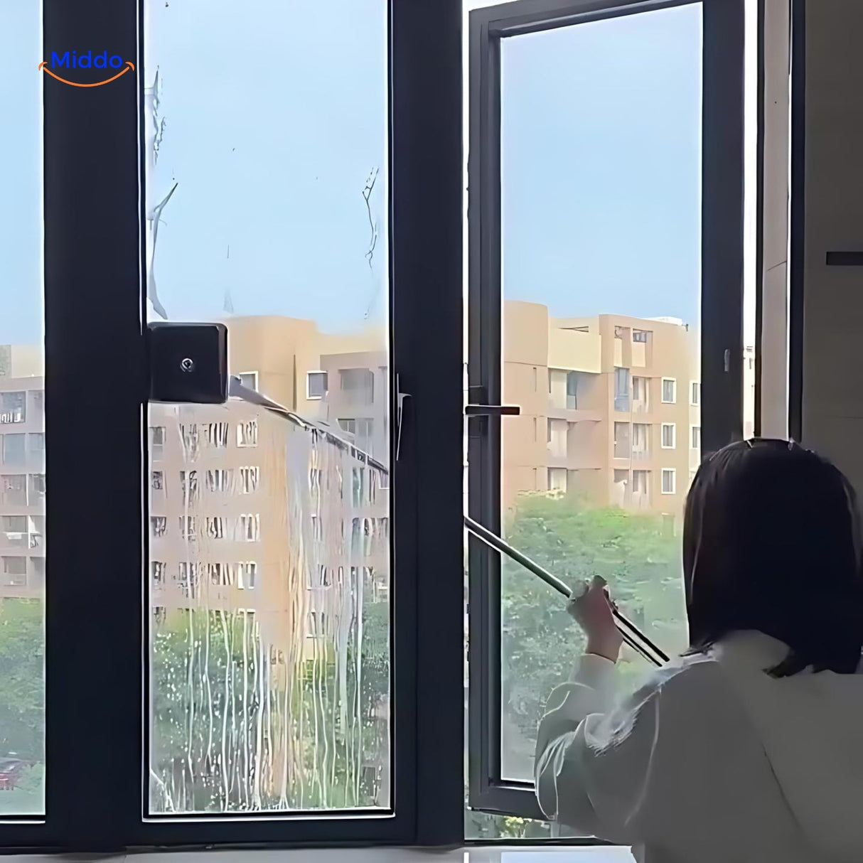 Woman using the double-sided magnetic window cleaner on apartment windows without safety risks.