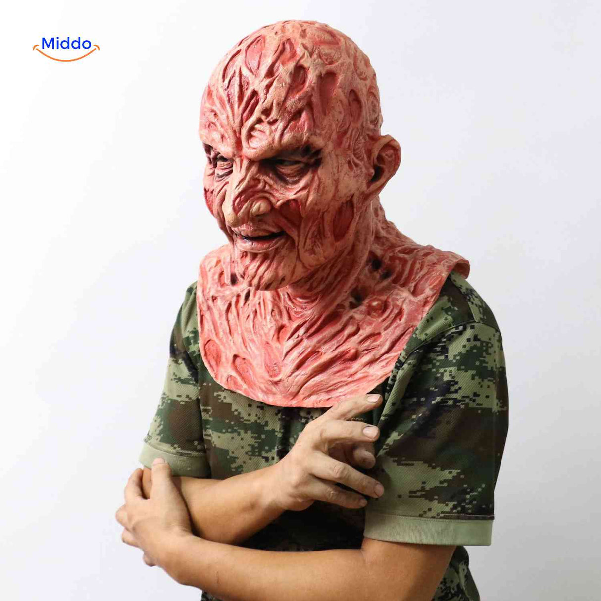 Person wearing Zombiora mask with camouflage shirt and hand touching mask.