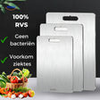 Three SafeCut stainless steel cutting boards in graduated sizes beside a basket of vegetables