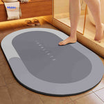 Light gray oval water-absorbing bath mat with reliable non-slip grip.