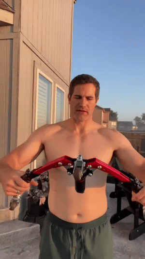 Man using arm trainer outdoors for strength training workout.