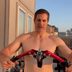Man using arm trainer outdoors for strength training workout.