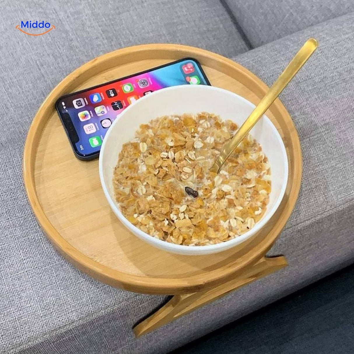 ComfyGrip sofa armrest table with breakfast bowl and smartphone on bamboo surface.