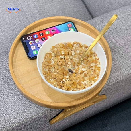 ComfyGrip sofa armrest table with breakfast bowl and smartphone on bamboo surface.