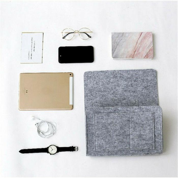 BedCaddy organizing magazines, phone, and glasses at bedside in light gray.