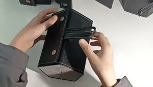 Hands demonstrating the fold-open mechanism of a black 6-slot multi-compartment eyeglasses case.