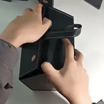 Demo of a black foldable multi-compartment eyeglasses case being held by its handle, showing portability.