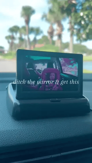 Baby car monitor mounted on dashboard with live backseat view.