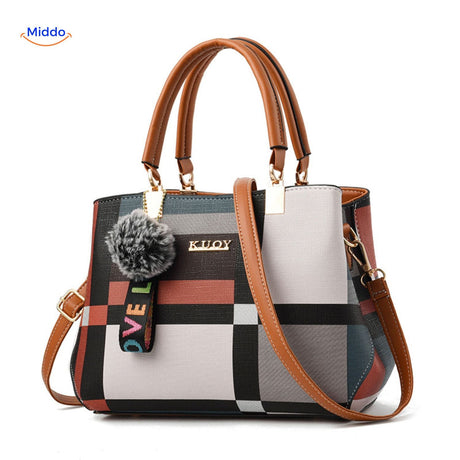 Chic tote handbag with bold contrast colors and pom-pom accent.