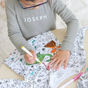 Dinosaur-theme color-your-own pajama being colored by child.