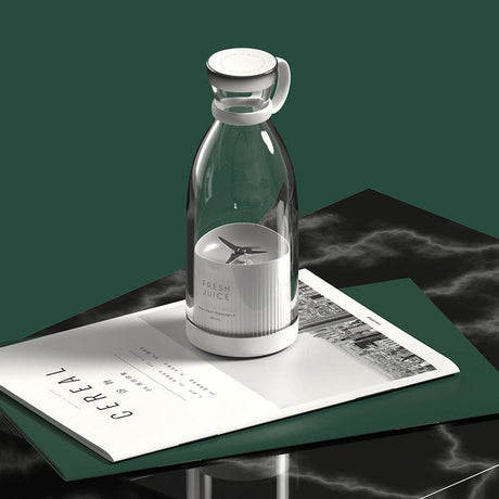 Portable cordless blender displayed on desk with books and home styling.