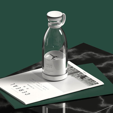 Portable cordless blender displayed on desk with books and home styling.
