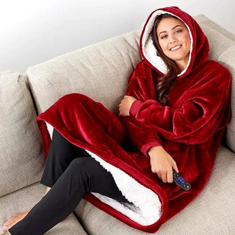 Woman wearing cozy oversized sherpa fleece hoodie while relaxing on couch at home.