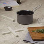 Cream-colored wooden trivet protecting countertop with hot cookware in use.