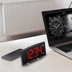 LED alarm clock positioned on a tabletop, showing curved design and time display.