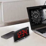 LED alarm clock positioned on a tabletop, showing curved design and time display.