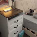 Sleep aid speaker on nightstand emitting warm glow light for peaceful bedroom environment