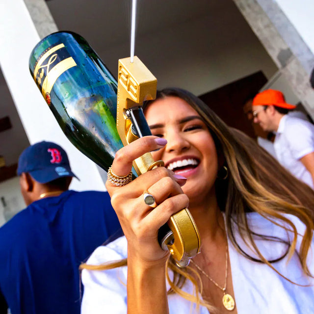 Woman spraying beer with beergun drink dispenser at party