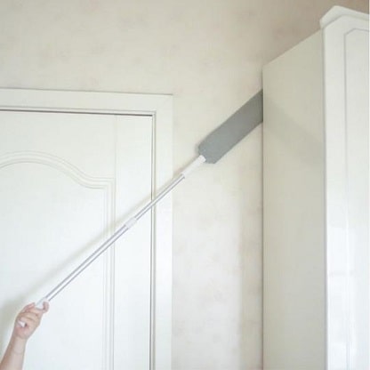 Telescopic duster cleaning dust behind and between furniture.