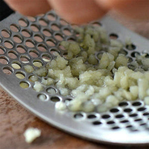 HandyPress garlic press being used to mince fresh garlic cloves efficiently.