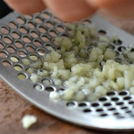 HandyPress garlic press being used to mince fresh garlic cloves efficiently.