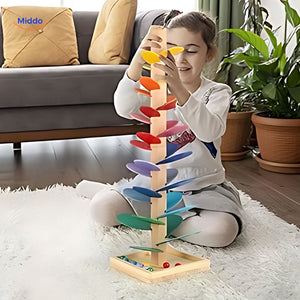 Girl placing glass balls through wooden ball run tree.