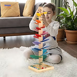 Girl placing glass balls through wooden ball run tree.