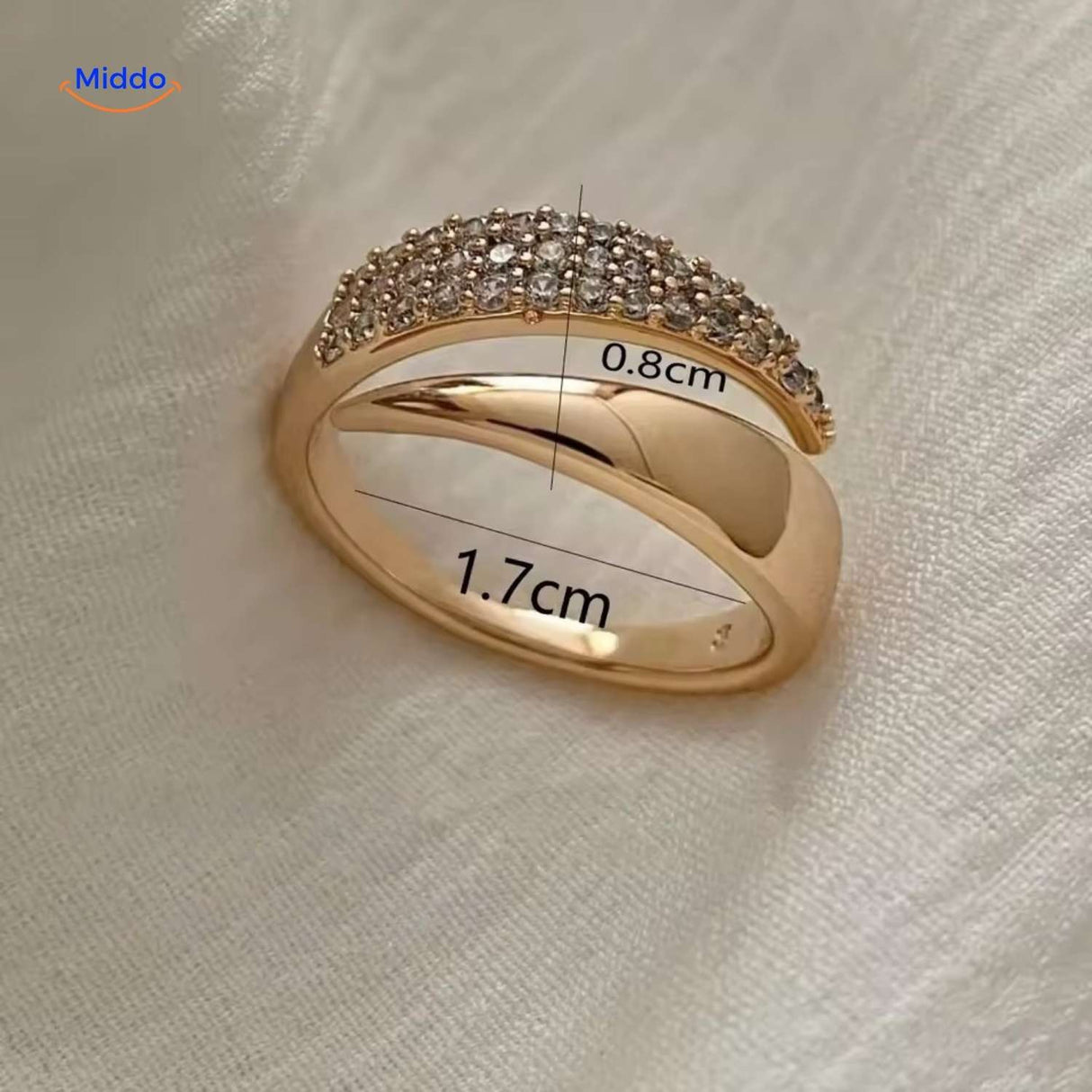 Gold adjustable ring with zirconia stones showing sizing on fabric.