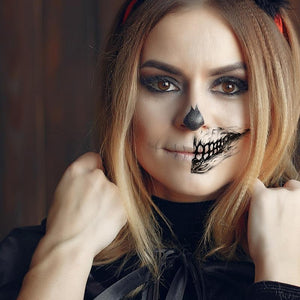 Realistic Halloween temporary tattoo featuring skull and grin design on woman's face.
