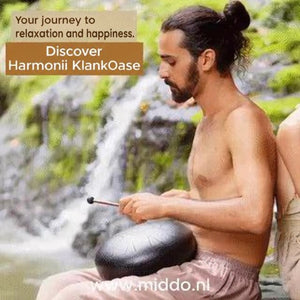 Man playing a Harmonii steel tongue drum beside a waterfall.