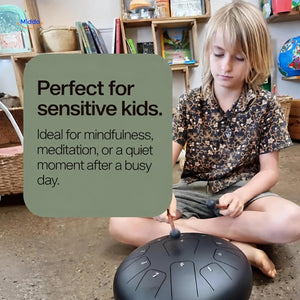 Child playing a black steel tongue drum with mallets during a quiet moment.