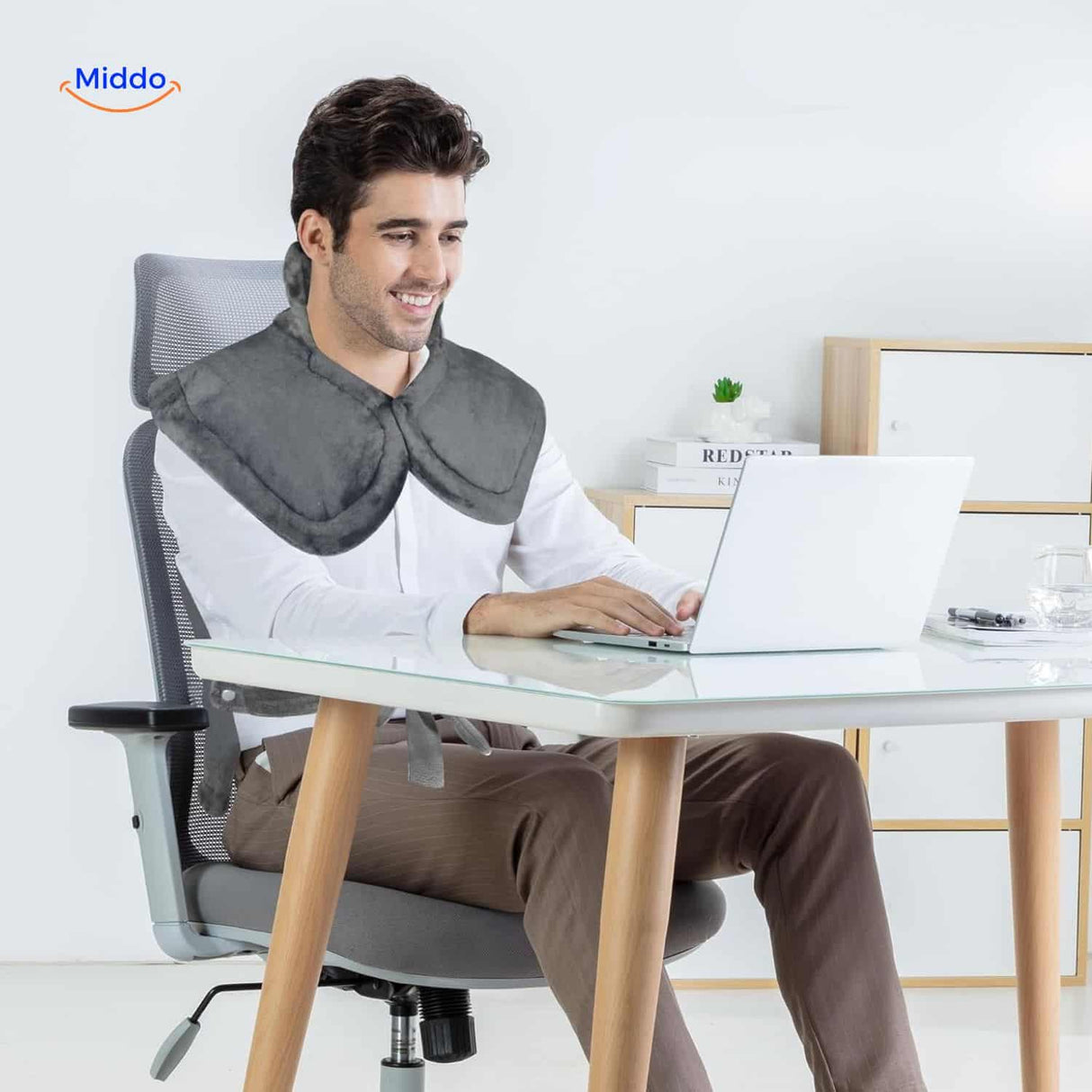 Person wearing heating pad at desk while working for improved neck and shoulder support.