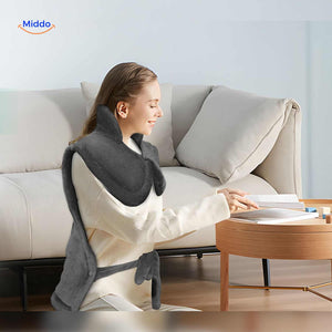 Person relaxing at home reading while using the electric heating pad for neck and shoulder comfort.