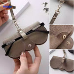 Slim leather case shown in lifestyle setting with reading glasses and accessories.