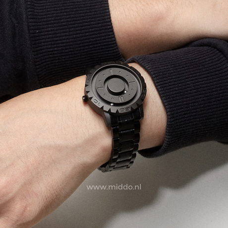 Black magnetic watch worn on wrist, showing face-on view and band.