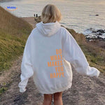 White oversized hoodie with orange motivational text.