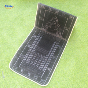 Compact padded travel prayer mat in dark grey, shown folded for travel.