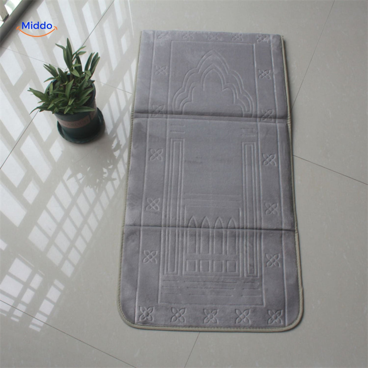 Compact padded travel prayer mat in grey, folded neatly for travel or outdoor use.