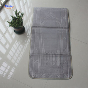 Compact padded travel prayer mat in grey, folded neatly for travel or outdoor use.