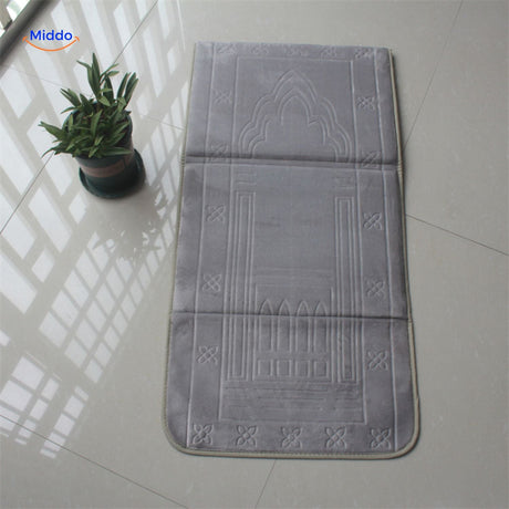 Compact padded travel prayer mat in grey, folded neatly for travel or outdoor use.