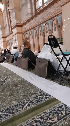Padded travel prayer mat in use during group prayer inside a mosque.