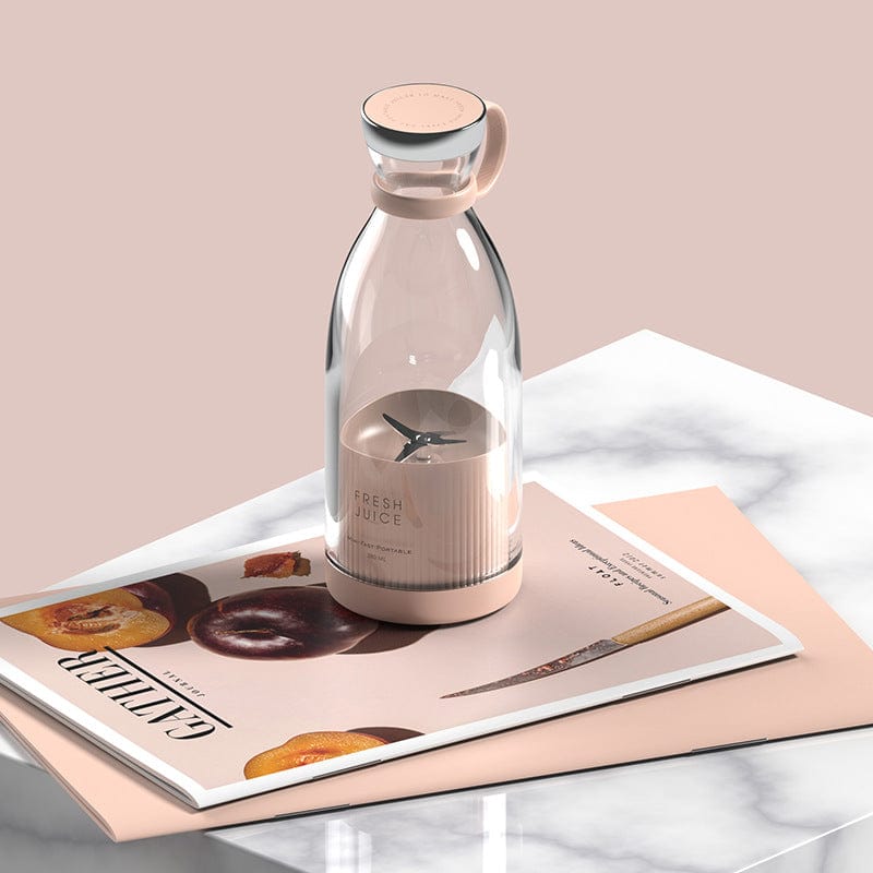 Cordless portable blender styled on desk next to magazines and home decor.