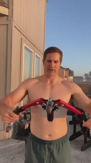Man using arm trainer outdoors for strength training workout.