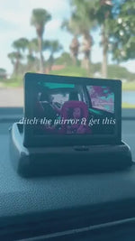 Baby car monitor mounted on dashboard with live backseat view.