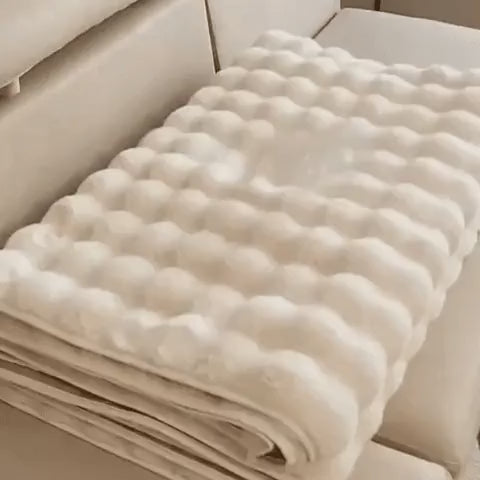 Beige plush furniture cover neatly folded for compact storage and easy transport.